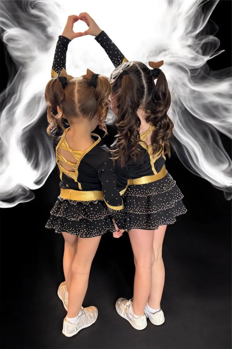 Two young Elite Cheer athletes in black-and-gold uniforms forming a heart